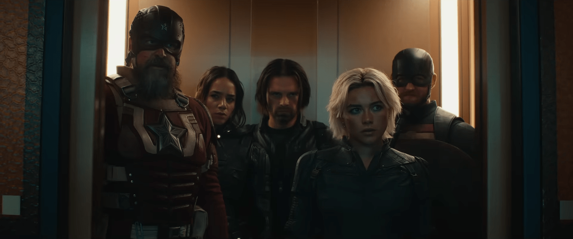 The Thunderbolts team standing together inside an elevator: David Harbour as Red Guardian, Olga Kurylenko as Taskmaster, Sebastian Stan as Bucky Barnes, Florence Pugh as Yelena Belova, and Wyatt Russell as U.S. Agent.