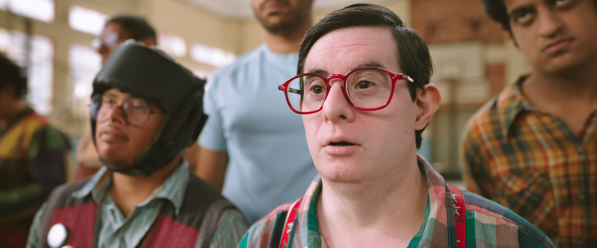 A close-up of a basketball team member wearing bright red glasses, saying "The New Coach is a fool".