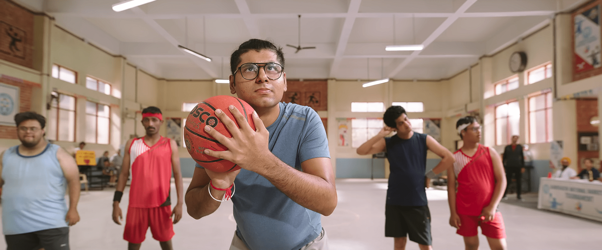 A player from the special-needs basketball team prepares to take a focused shot during practice, with teammates watching in the background.